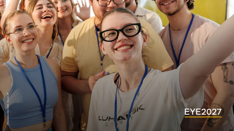 Grupa uśmiechniętych młodych ludzi; na pierwszym planie dziewczyna w okularach robiąca selfie całej grupie.